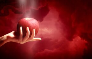 A woman’s hand holding a red apple against a smokey red backdrop.