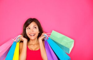 A happy woman holding colorful shopping bags is good for retail stocks