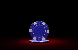 A blue poker chip against a dark red and black background representing the disadvantages of blue chip stocks.